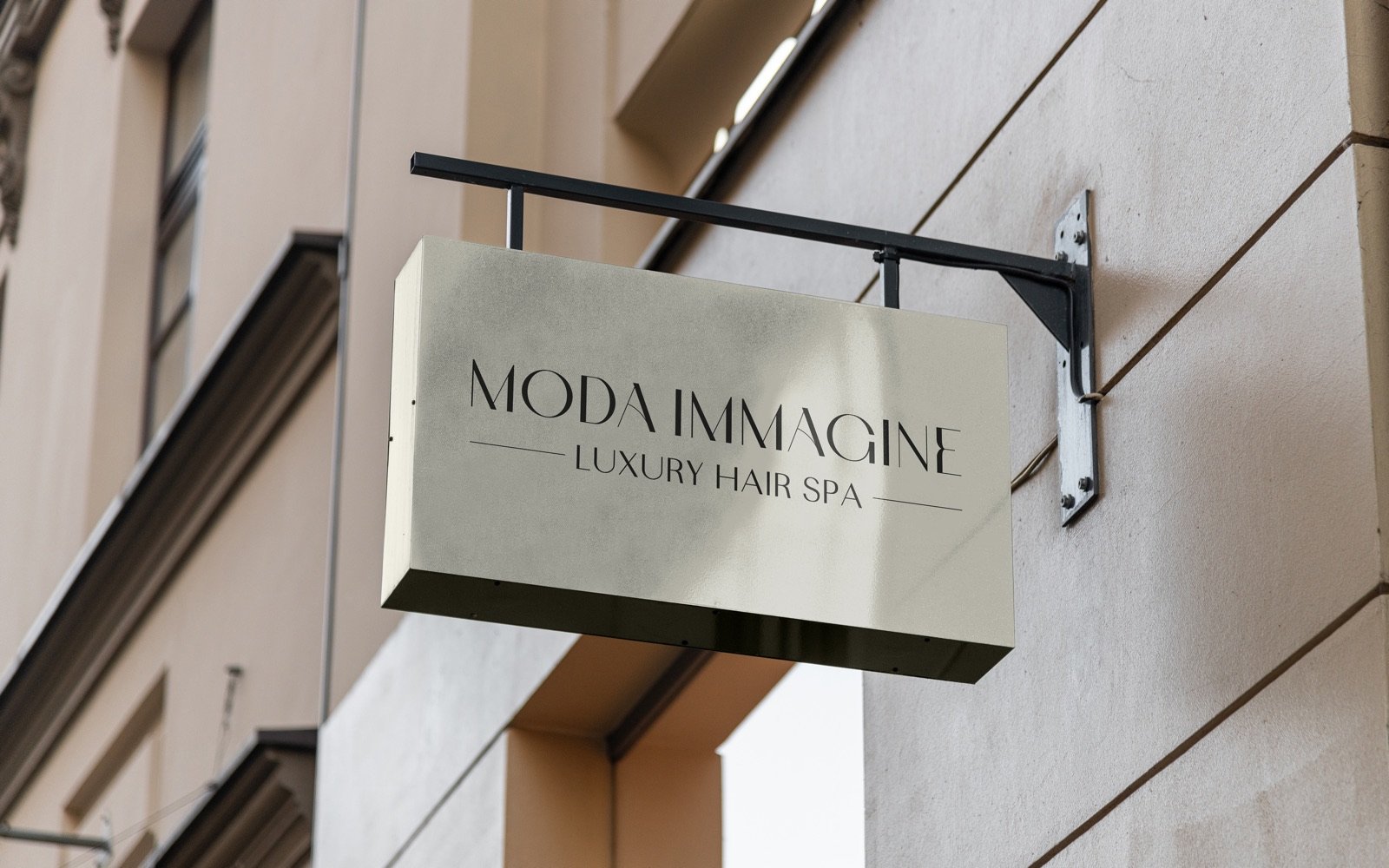 Insegna a bandiera avorio agganciata alla facciata con un braccio in ferro nero: sopra, in scuro, MODA IMMAGINE e sotto LUXURY HAIR SPA fra due filetti.