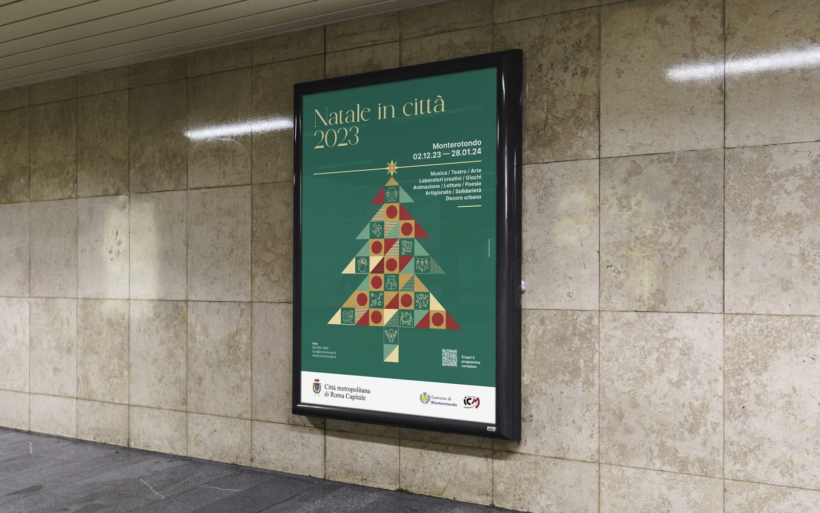 Manifesto in una bacheca illuminata su un muro di travertino: fondo verde, titolo Natale in città 2023 in oro, un albero di Natale composto da triangoli e quadrati verdi, rossi e oro con dentro delle icone, e la riga Monterotondo 02.12.23 — 28.01.24.