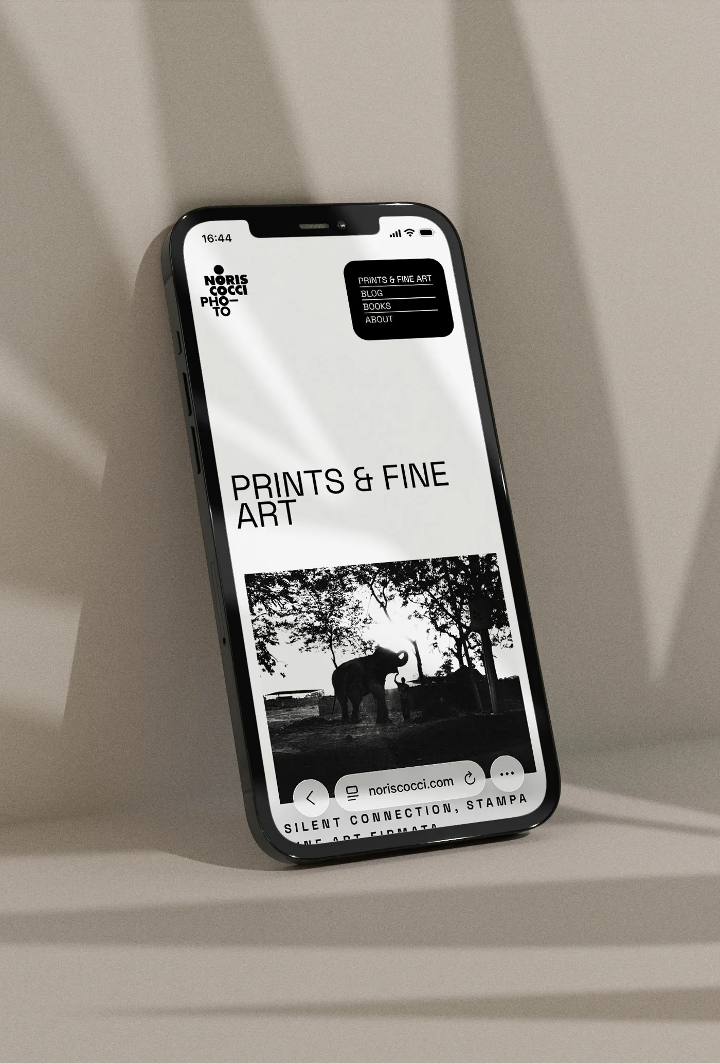 Mock-up: la stessa sezione sul telefono, appoggiato in verticale contro una parete di travertino: il menu resta in alto a destra, le fotografie si incolonnano una sotto l'altra e le didascalie vanno a capo.